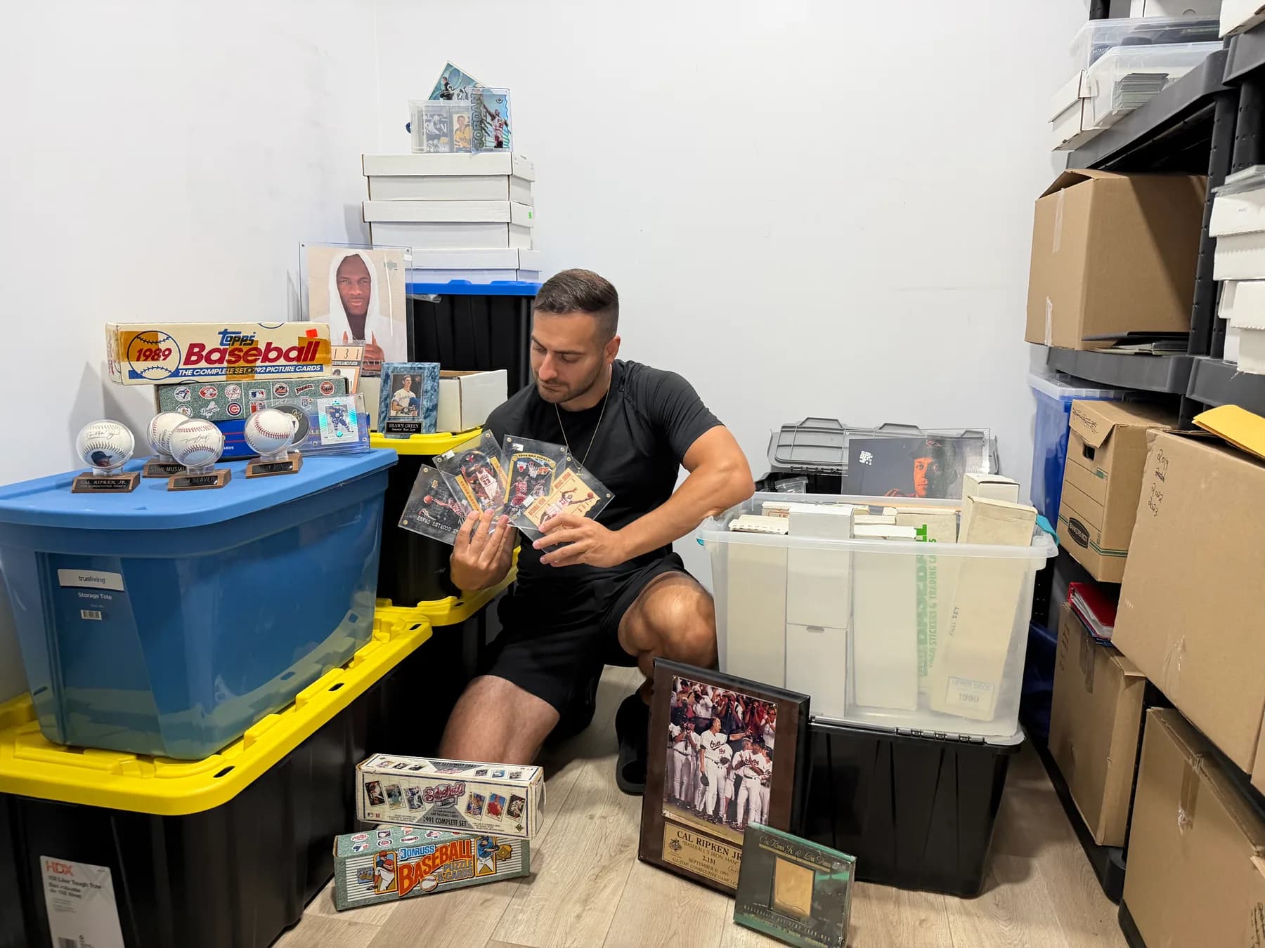 The collector in the vault holding classic Michael Jordan cards, surrounded by sealed storage boxes, signed baseballs, and factory sets